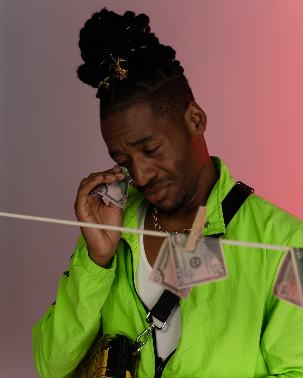 man in green jacket wiping his tears using banknote